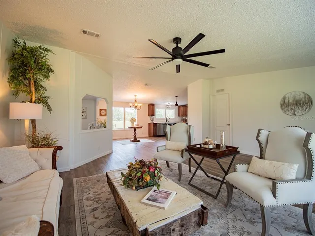 a kitchen with kitchen island granite countertop a sink dishwasher a stove and a dining table with wooden floor