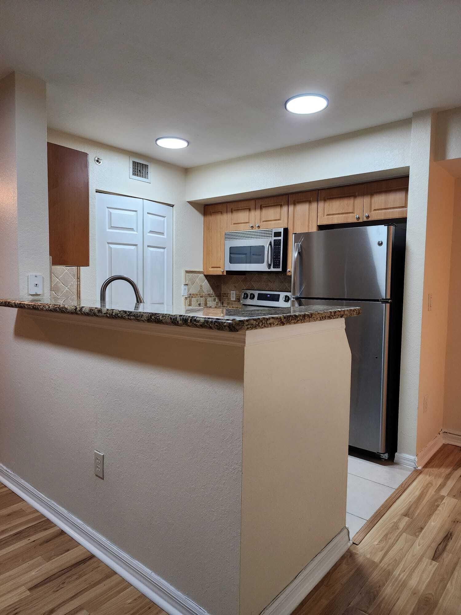 6777 Heritage Grande, Unit 1208 Boynton Beach, FL 33437 - Photo 5 of 17 a kitchen with stainless steel appliances a sink and a microwave