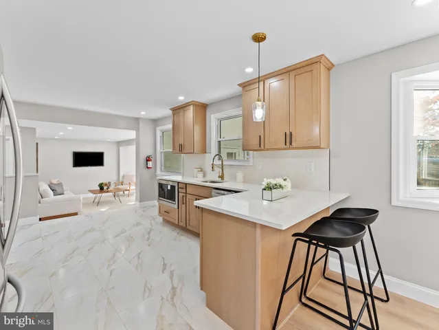 a large white kitchen with stainless steel appliances granite countertop a stove and a sink