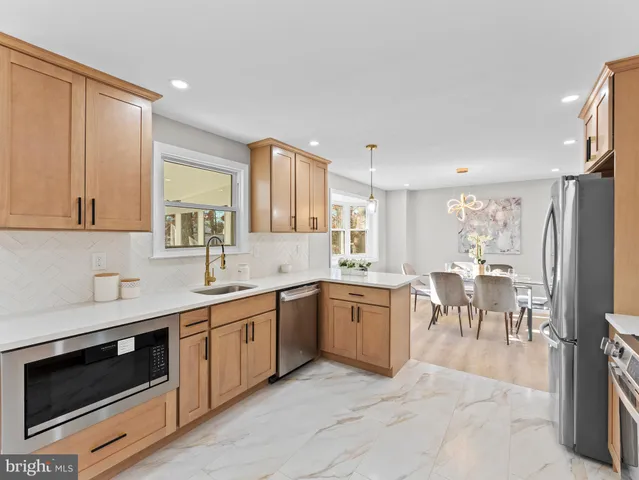 a large white kitchen with stainless steel appliances granite countertop a stove and a sink with granite countertops