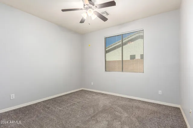 an empty room with a window and a fan