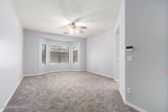 en empty room with windows and ceiling fan