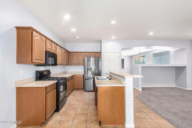 a kitchen with stainless steel appliances granite countertop a refrigerator a sink dishwasher and a stove with wooden cabinets