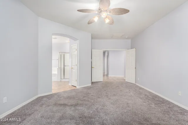 a view of an empty room and chandelier fan