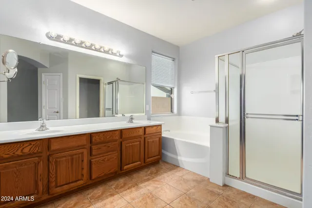 a spacious bathroom with a double vanity sink a mirror and a bathtub