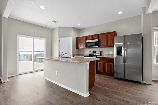 a kitchen with stainless steel appliances granite countertop a refrigerator a sink a stove top oven and a refrigerator