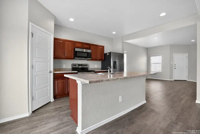 a living room with stainless steel appliances kitchen island granite countertop a stove a sink a refrigerator and a microwave