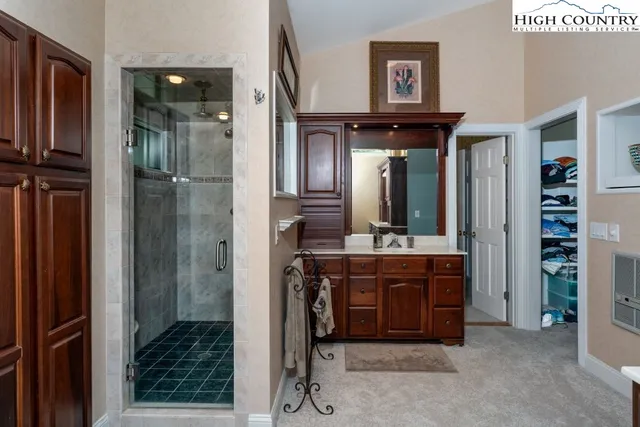 a bathroom with a mirror a sink and a glass door shower