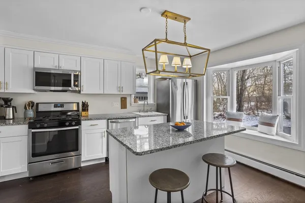 a kitchen with stainless steel appliances granite countertop a stove top oven a sink dishwasher a dining table and chairs with wooden floor