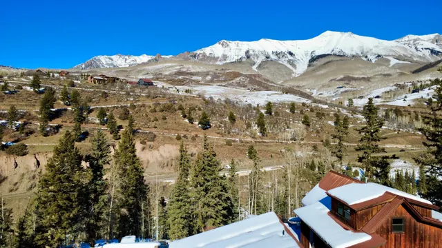 a view of a house with a yard and mountain view in back