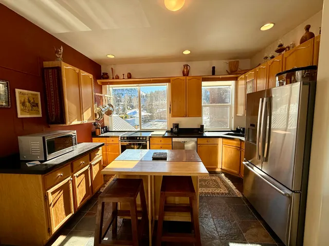 a kitchen with stainless steel appliances granite countertop a refrigerator a sink a stove and island