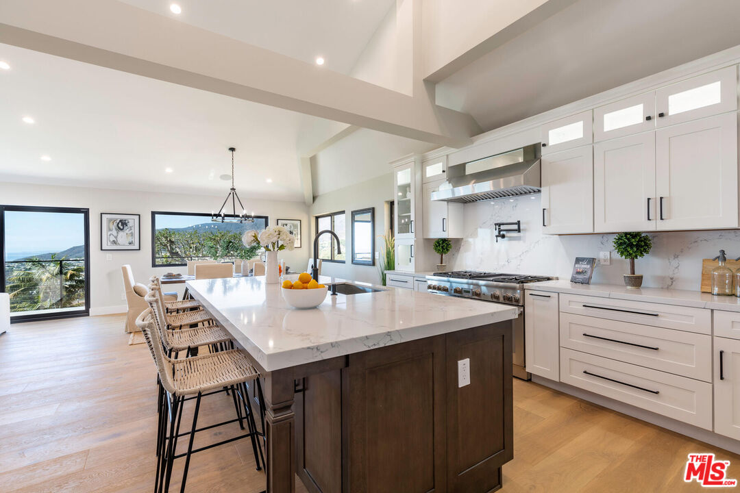 243 Notteargenta Road Pacific Palisades, CA 90272 - Photo 7 of 46 a kitchen with stainless steel appliances stove refrigerator dining table and chairs