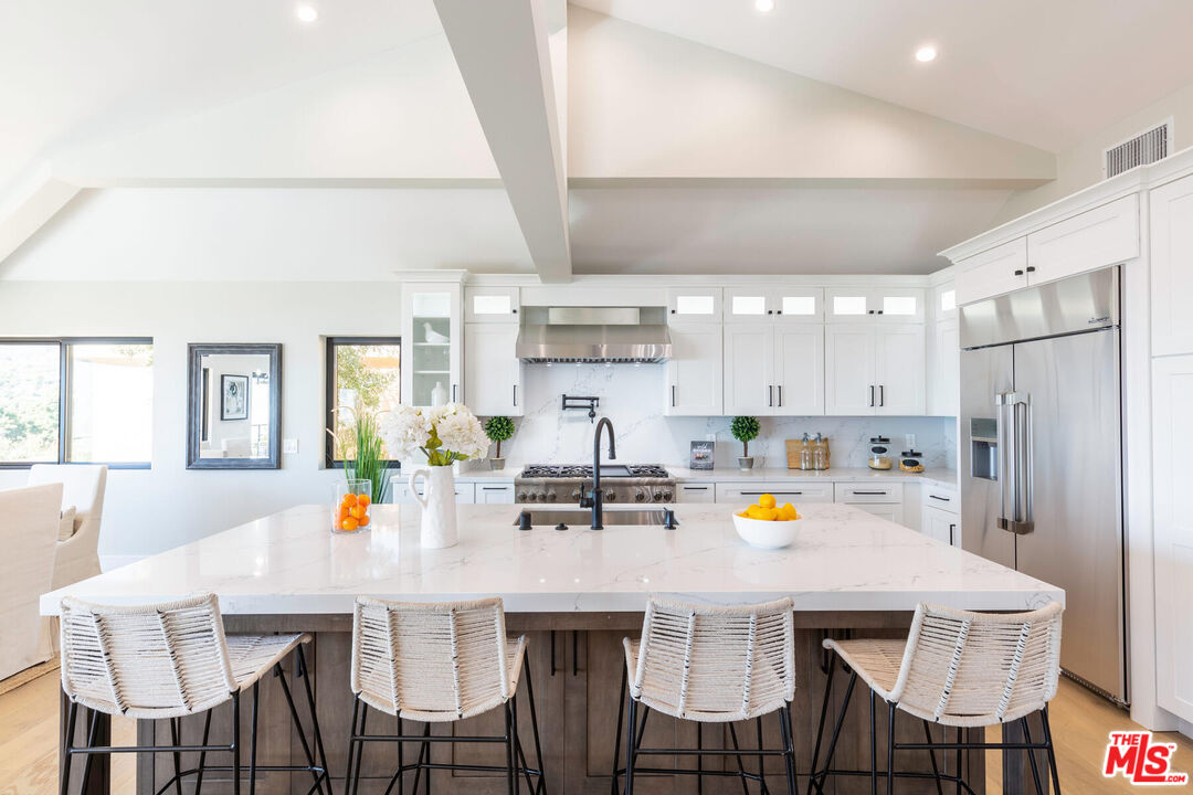 243 Notteargenta Road Pacific Palisades, CA 90272 - Photo 8 of 46 a kitchen with stainless steel appliances a dining table and chairs