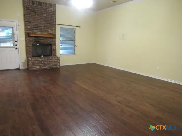 a view of empty room with wooden floor and fireplace