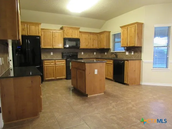 a kitchen with stainless steel appliances granite countertop a stove top oven a refrigerator a sink and dishwasher