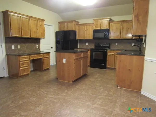 a kitchen with stainless steel appliances granite countertop a stove top oven a sink a counter space and cabinets