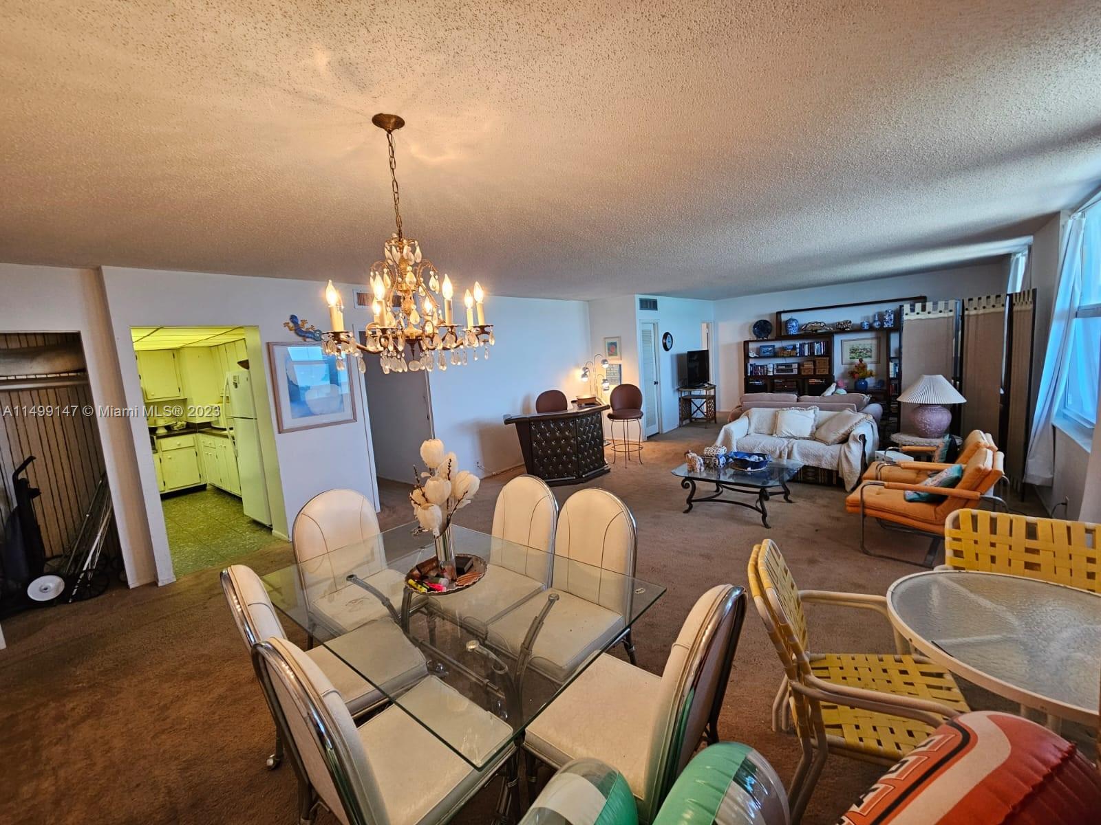9511 Collins Avenue, Unit 403 Surfside, FL 33154 - Photo 12 of 52 a living room with furniture and a chandelier