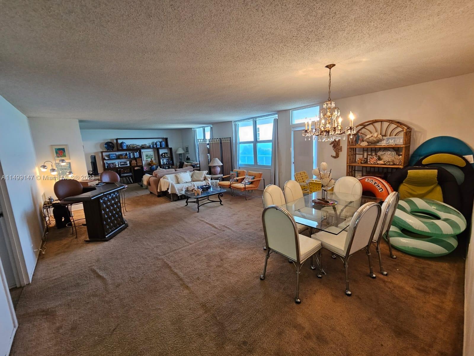 9511 Collins Avenue, Unit 403 Surfside, FL 33154 - Photo 15 of 52 a living room with furniture and a chandelier