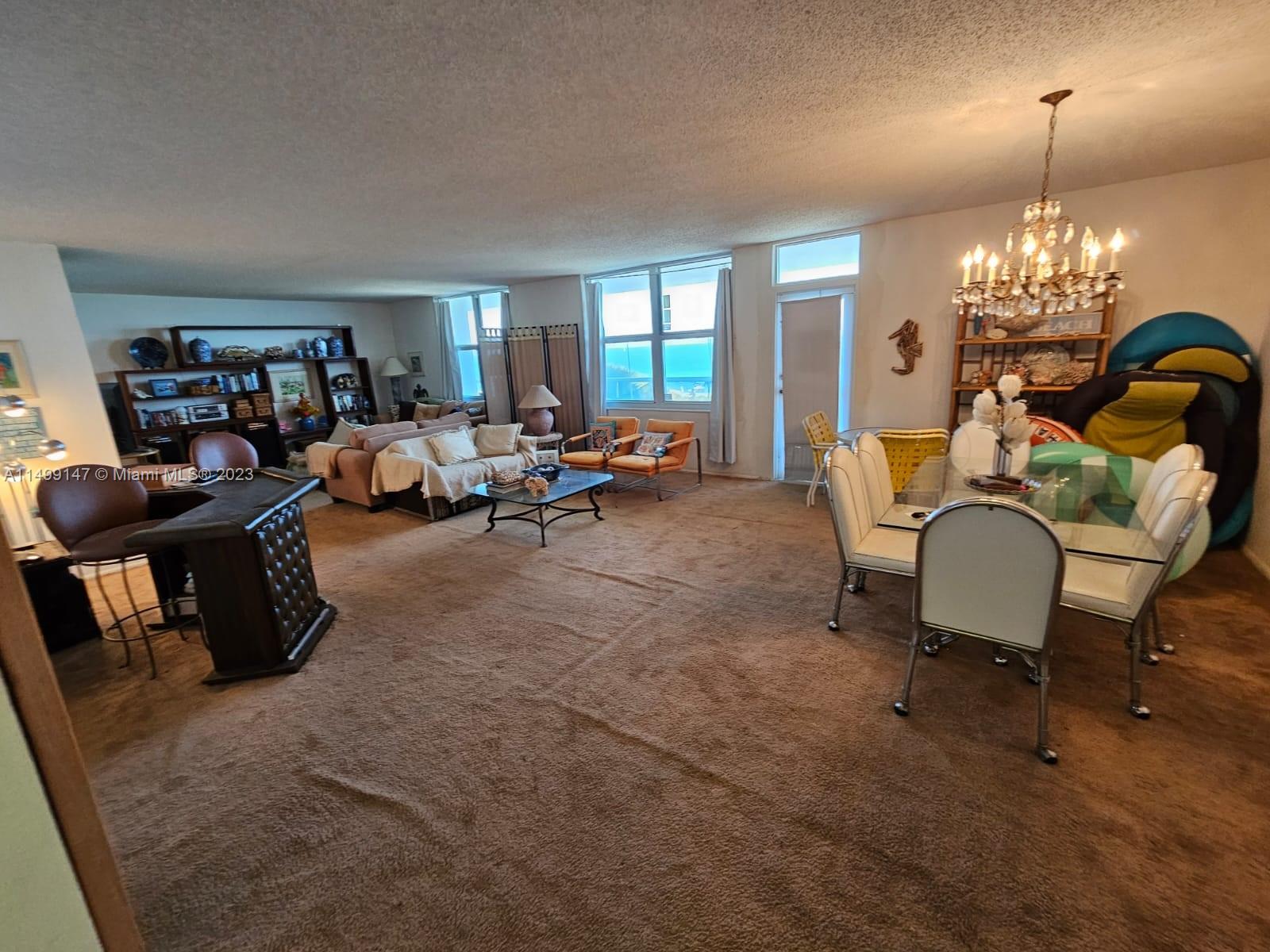 9511 Collins Avenue, Unit 403 Surfside, FL 33154 - Photo 16 of 52 a living room with furniture and a chandelier