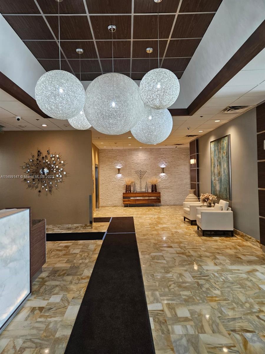 9511 Collins Avenue, Unit 403 Surfside, FL 33154 - Photo 3 of 52 a view of a room with wooden floor and chandelier