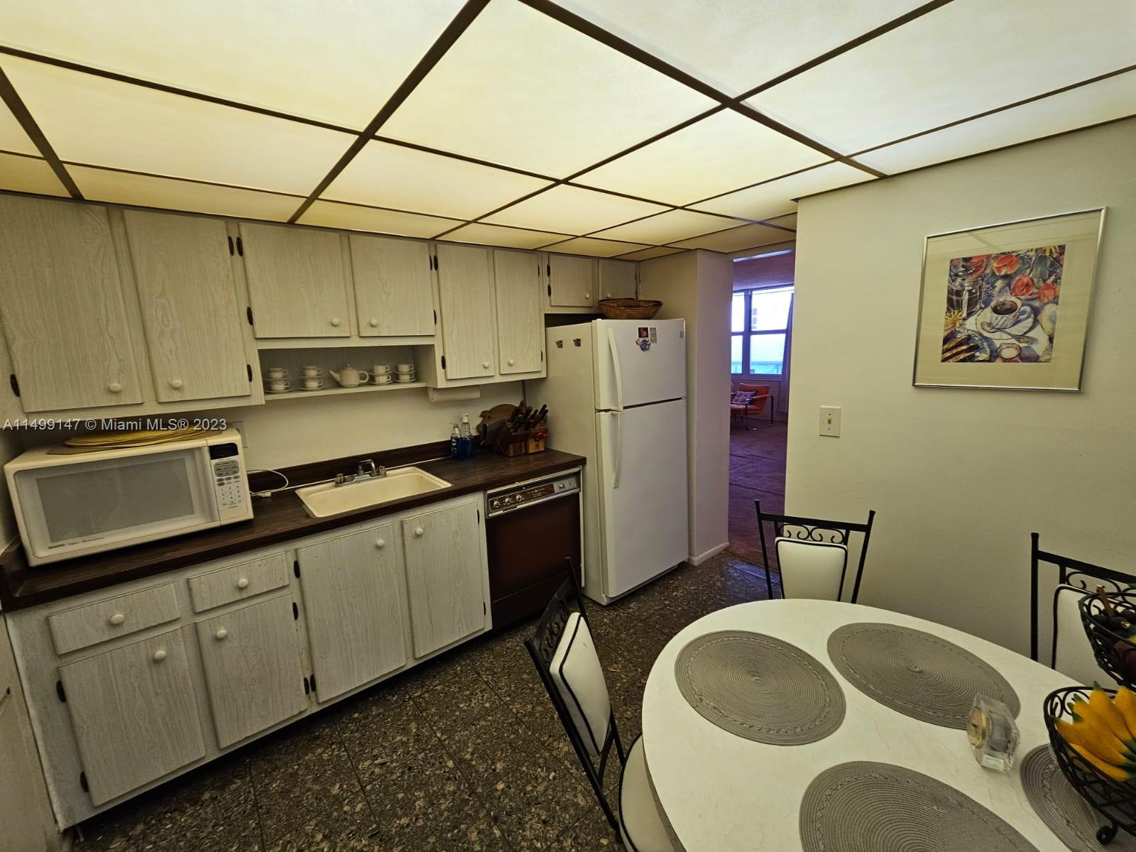 9511 Collins Avenue, Unit 403 Surfside, FL 33154 - Photo 7 of 52 a kitchen with stainless steel appliances granite countertop a sink a refrigerator and cabinets