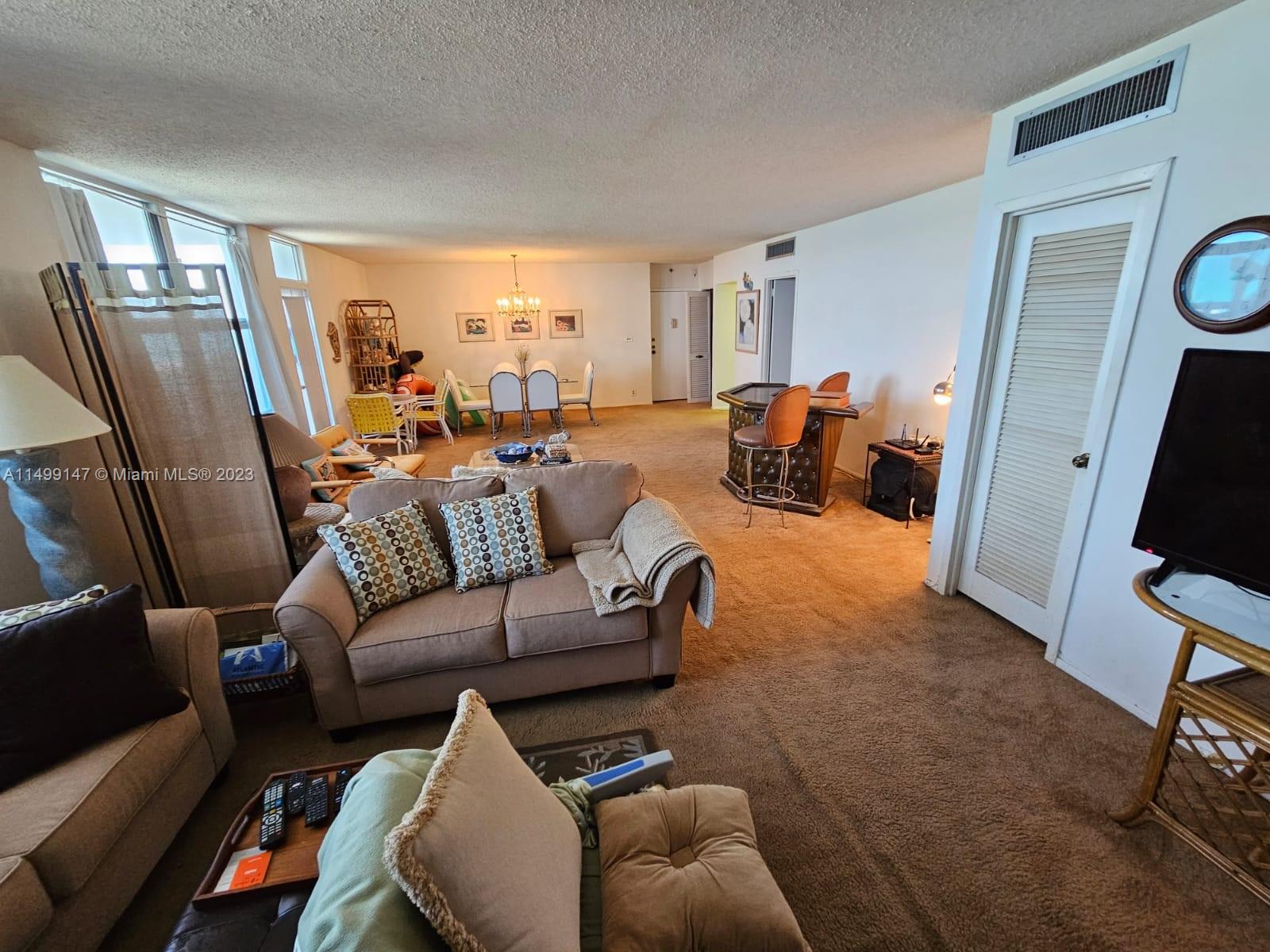 9511 Collins Avenue, Unit 403 Surfside, FL 33154 - Photo 8 of 52 a living room with furniture and a flat screen tv