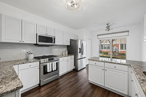 a kitchen with stainless steel appliances white cabinets a sink a stove a refrigerator and microwave