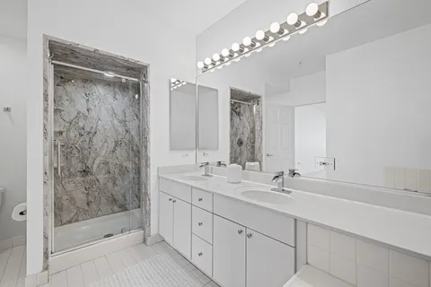 a bathroom with a double vanity sink mirror and shower