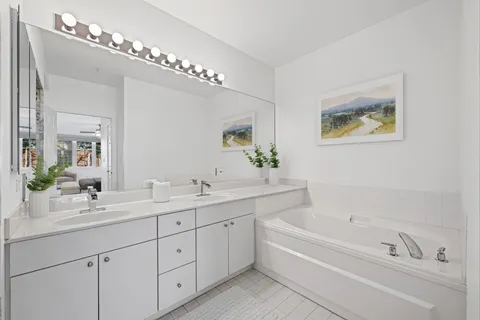 a bathroom with a double vanity sink mirror and bathtub