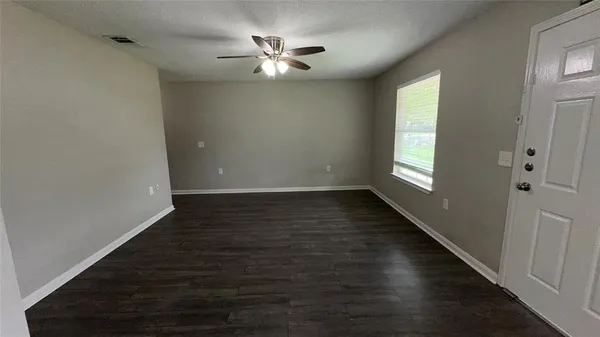 a view of an empty room with wooden floor and a window
