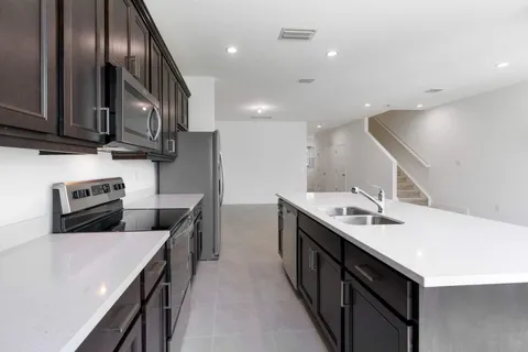 a kitchen with a refrigerator a stove top oven a sink and a window