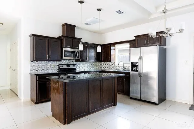 a kitchen with stainless steel appliances granite countertop a refrigerator a stove a sink and a microwave