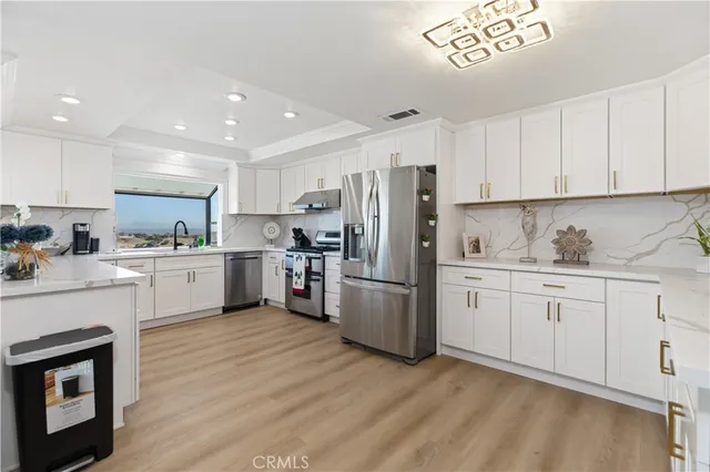 a kitchen with granite countertop white cabinets and stainless steel appliances