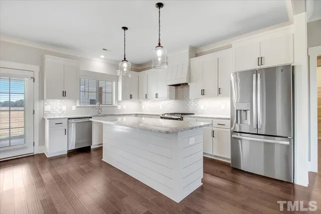 a large white kitchen with a stove a sink dishwasher a kitchen island with wooden floor and cabinets