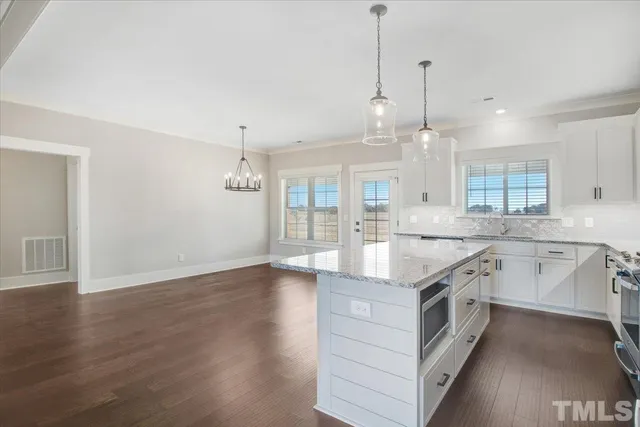 a kitchen with stainless steel appliances granite countertop a sink a oven a refrigerator and white cabinets