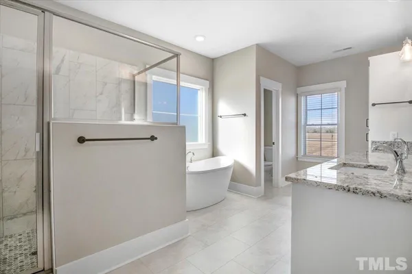 a spacious bathroom with a granite countertop sink a mirror and a bathtub