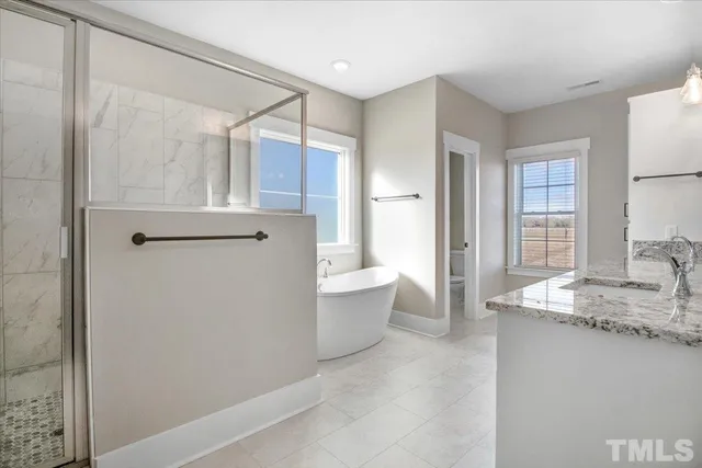 a spacious bathroom with a granite countertop sink a mirror and a bathtub