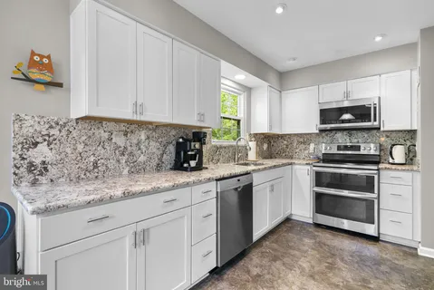 a kitchen with stainless steel appliances granite countertop a sink stove and microwave