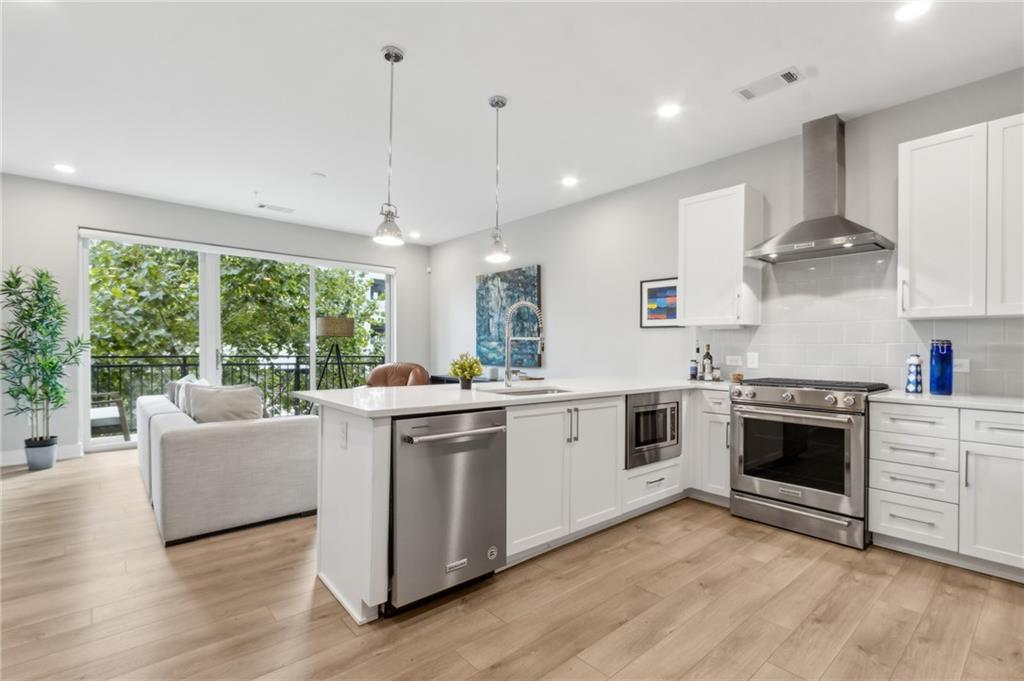 22 Airline Street Southeast, Unit 204 Atlanta, GA 30312 - Photo 6 of 34 a kitchen with stainless steel appliances granite countertop a stove a sink and white cabinets with wooden floors