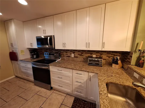 a kitchen with stainless steel appliances granite countertop a stove a sink and a microwave