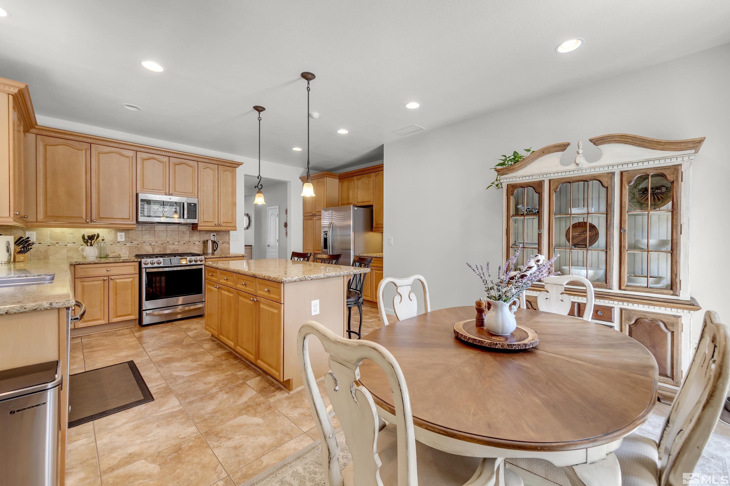 2100 Angel Ridge Drive Reno, NV 89521 - Photo 4 of 35 a kitchen with stainless steel appliances kitchen island granite countertop a sink a stove a dining table and chairs