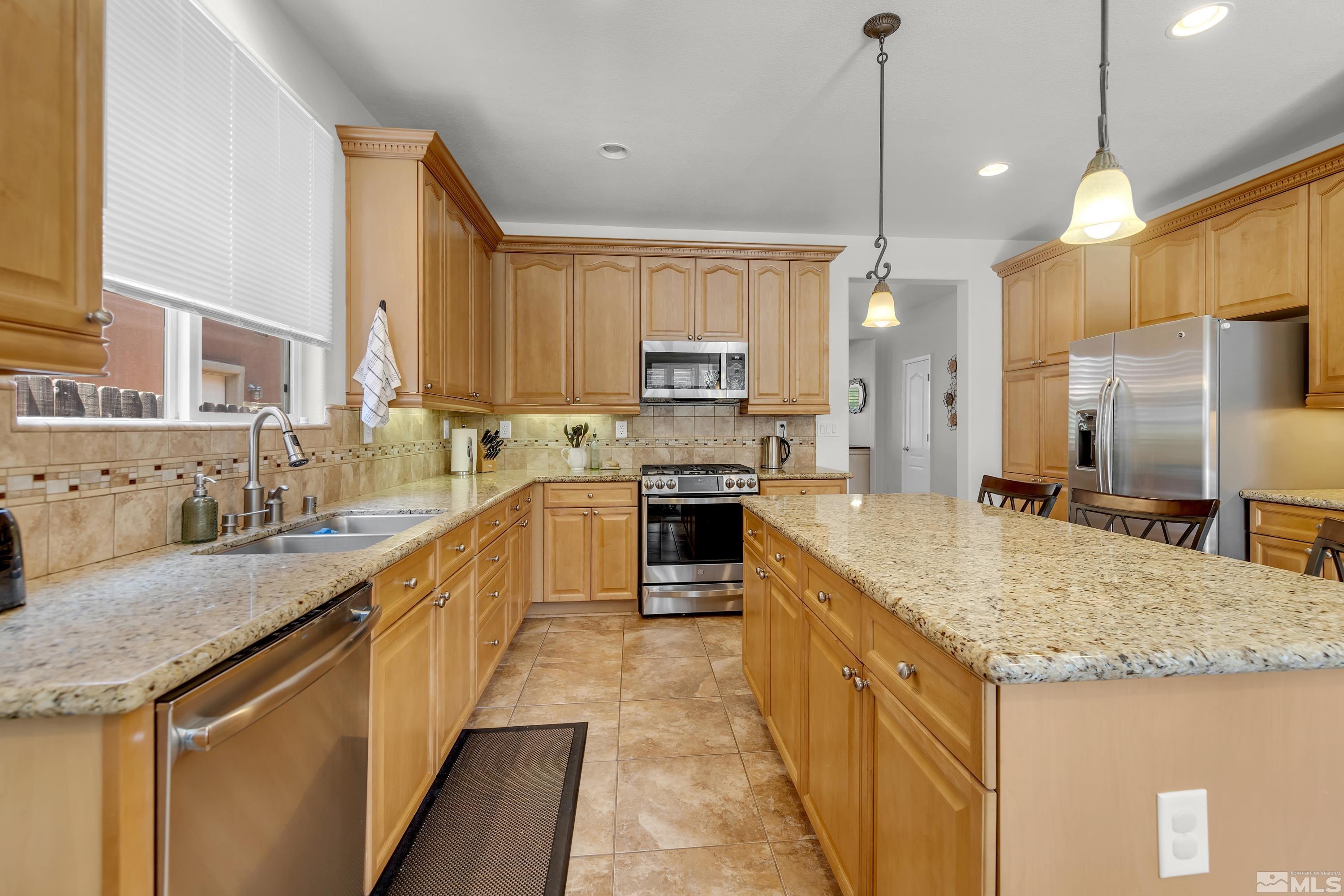 2100 Angel Ridge Drive Reno, NV 89521 - Photo 7 of 35 a kitchen with stainless steel appliances granite countertop a sink a stove and a refrigerator