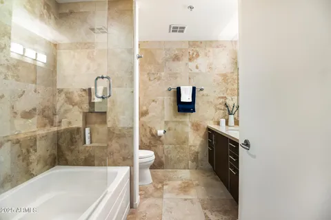 a bathroom with a granite countertop bathtub sink mirror and toilet