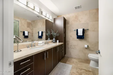 a spacious bathroom with a double vanity sink a mirror and a toilet
