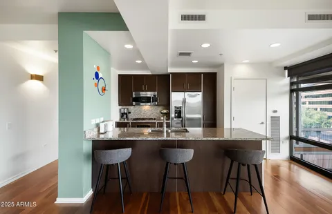 a kitchen with stainless steel appliances a dining table chairs refrigerator and sink