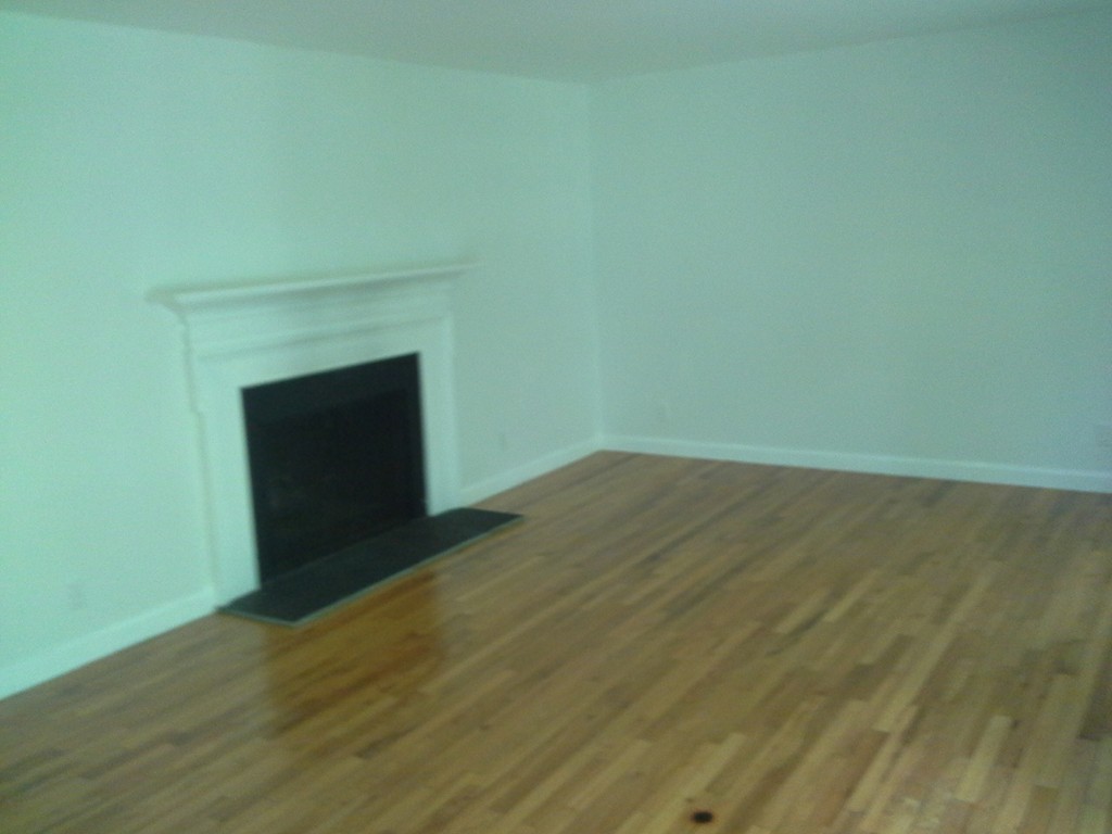 123 Jericho Road, Unit 123 Weston, MA 02493 - Photo 6 of 12 a view of an empty room with wooden floor and a fireplace