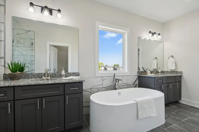 a bathroom with a granite countertop bathtub sink double and mirror