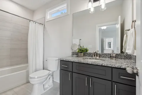 a bathroom with a granite countertop sink toilet a large mirror a bathtub and shower
