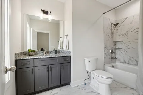 a bathroom with a granite countertop toilet a sink and a bathtub
