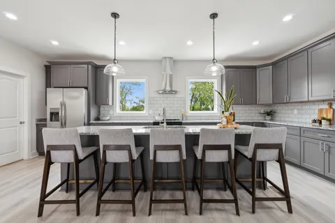 a kitchen with kitchen island a dining table chairs and white cabinets
